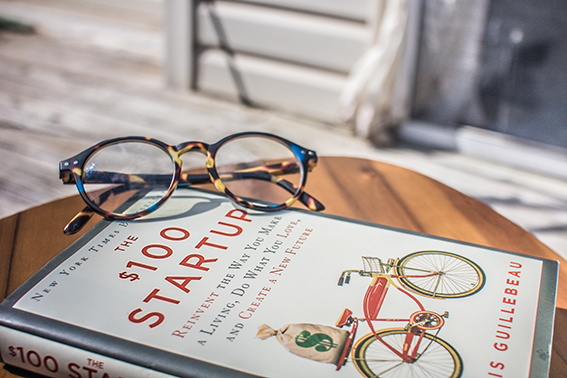 Tortoise shell round glasses sitting on a self help book about finances
