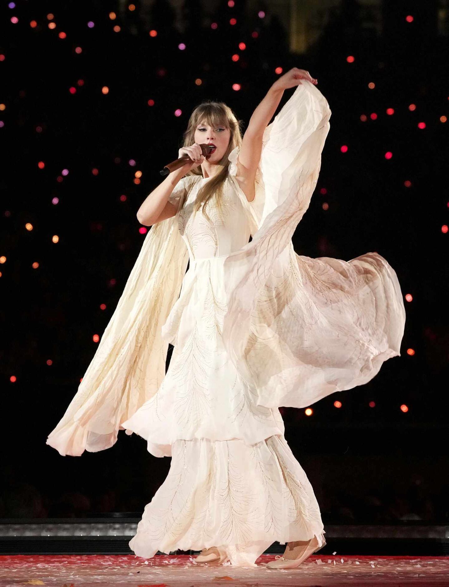 Taylor Swift performing on stage during the 'Eras Tour,' wearing a flowy purple gown with ruffled details, capturing the ethereal and whimsical essence of her 'Folklore' album era.